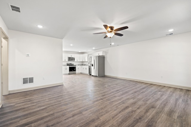 unfurnished living room featuring dark wood-type flooring and ceiling fan