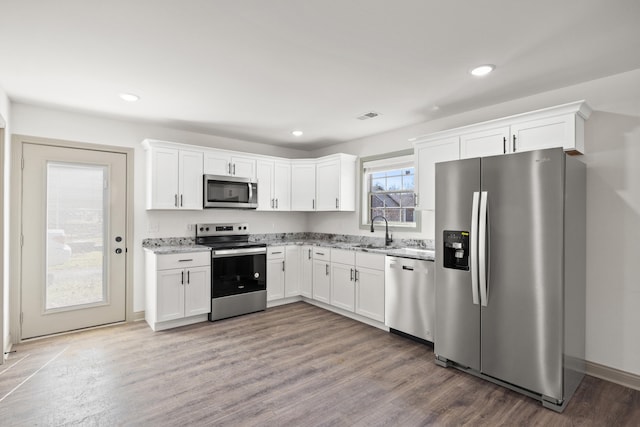 kitchen with light wood-type flooring, appliances with stainless steel finishes, sink, and white cabinets