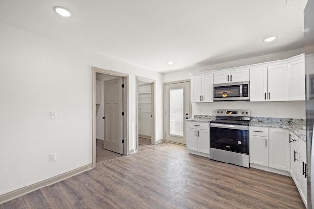 kitchen with stainless steel appliances, light stone countertops, and white cabinets