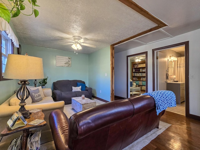 living room featuring hardwood / wood-style flooring, ceiling fan, and a textured ceiling