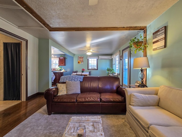 living room with ceiling fan, a textured ceiling, wood-type flooring, and a wall mounted AC