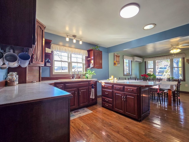 kitchen featuring hardwood / wood-style flooring, kitchen peninsula, sink, and a wall unit AC