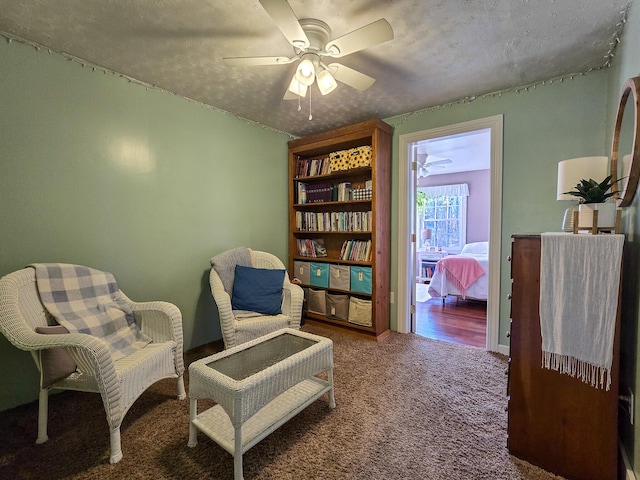 living area with carpet, a textured ceiling, and ceiling fan