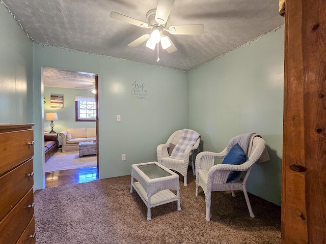 sitting room featuring a textured ceiling, carpet floors, and ceiling fan