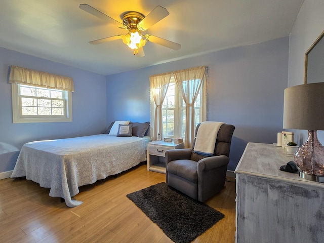 bedroom with multiple windows, hardwood / wood-style floors, and ceiling fan