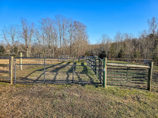 view of gate with a rural view and a lawn