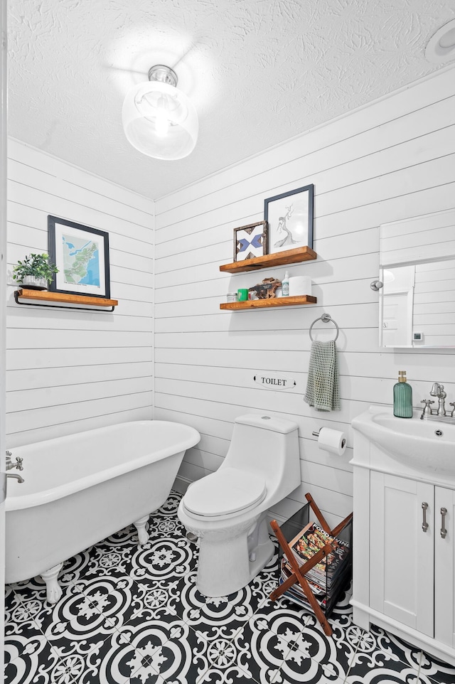 bathroom featuring tile patterned flooring, vanity, a washtub, toilet, and a textured ceiling