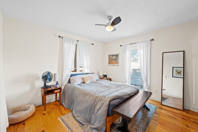 bedroom with ceiling fan, light hardwood / wood-style flooring, a textured ceiling, and access to outside