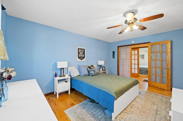 bedroom with ceiling fan, light hardwood / wood-style floors, french doors, and a textured ceiling