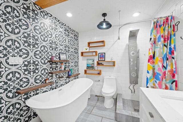 bathroom featuring tile walls, vanity, toilet, a bath, and tile patterned floors