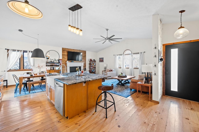 kitchen with pendant lighting, sink, a breakfast bar, dishwasher, and dark stone counters