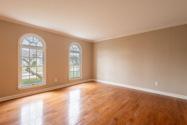 spare room with crown molding and light wood-type flooring