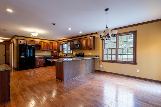 kitchen featuring hanging light fixtures, light hardwood / wood-style flooring, black appliances, and ornamental molding