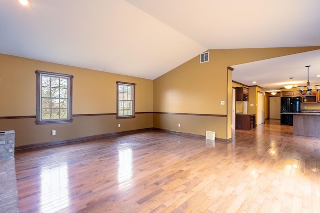 unfurnished living room featuring a chandelier, vaulted ceiling, and hardwood / wood-style floors