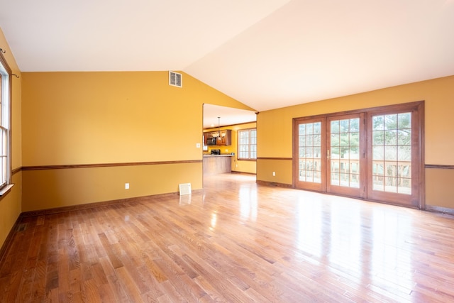 unfurnished living room with a healthy amount of sunlight, vaulted ceiling, and light wood-type flooring