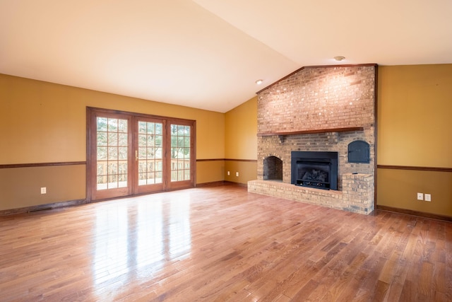 unfurnished living room featuring lofted ceiling, hardwood / wood-style floors, and a fireplace