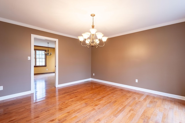 empty room featuring crown molding, wood-type flooring, and a chandelier