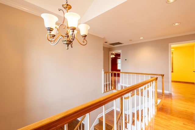 hallway featuring ornamental molding, hardwood / wood-style floors, and an inviting chandelier