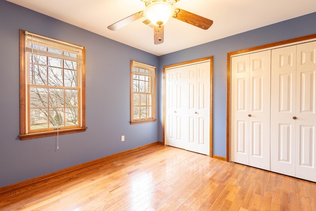 unfurnished bedroom with ceiling fan, two closets, and light wood-type flooring