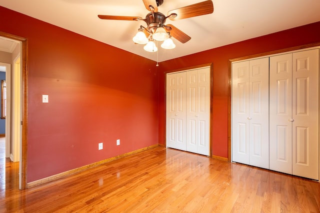 unfurnished bedroom with ceiling fan, two closets, and light hardwood / wood-style floors