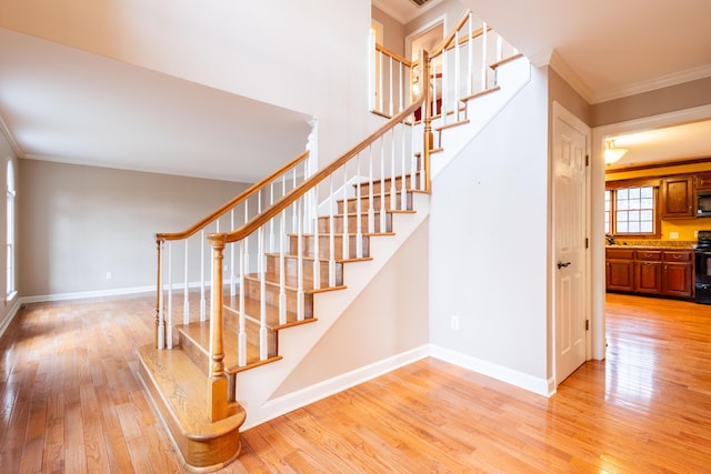 stairway with crown molding and wood-type flooring