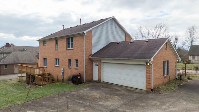 back of property featuring a garage, a yard, and a deck