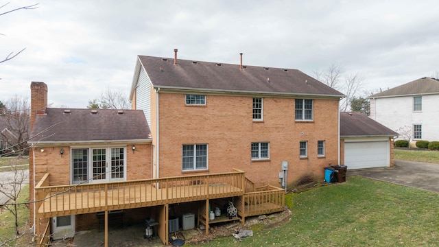 back of property featuring a garage, a lawn, central AC, and a deck