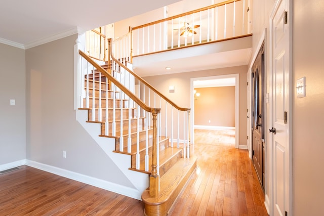 stairway with ornamental molding, hardwood / wood-style floors, and a high ceiling