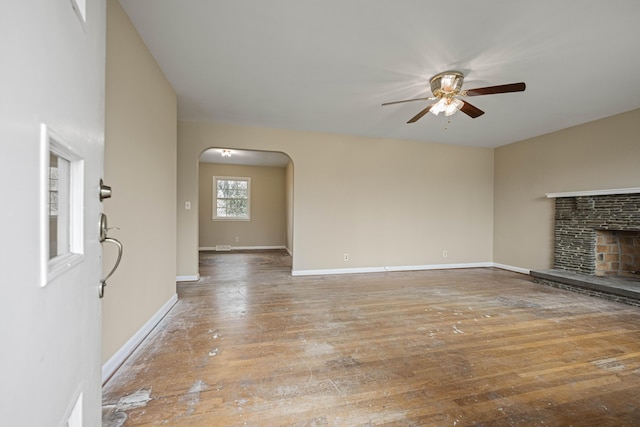 unfurnished living room with a stone fireplace, hardwood / wood-style floors, and ceiling fan