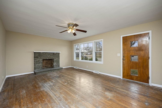 unfurnished living room with a brick fireplace, dark hardwood / wood-style floors, and ceiling fan