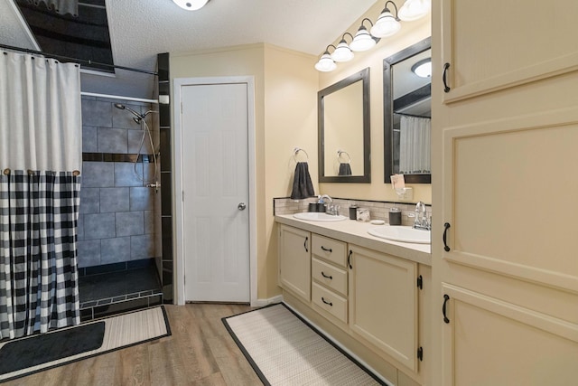 bathroom featuring hardwood / wood-style flooring, backsplash, vanity, a textured ceiling, and a shower with curtain