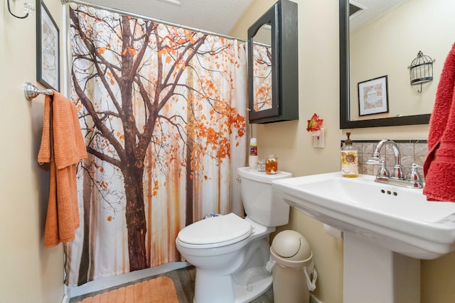 bathroom with sink, backsplash, and toilet