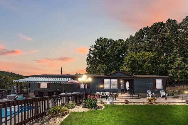 back house at dusk with a yard, a fenced in pool, and a patio area