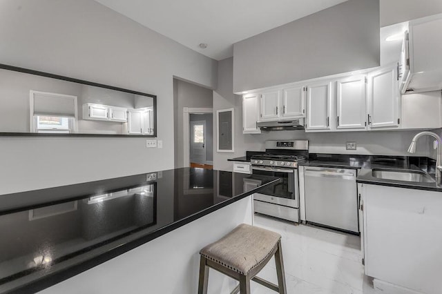 kitchen with appliances with stainless steel finishes, sink, white cabinets, and a kitchen breakfast bar