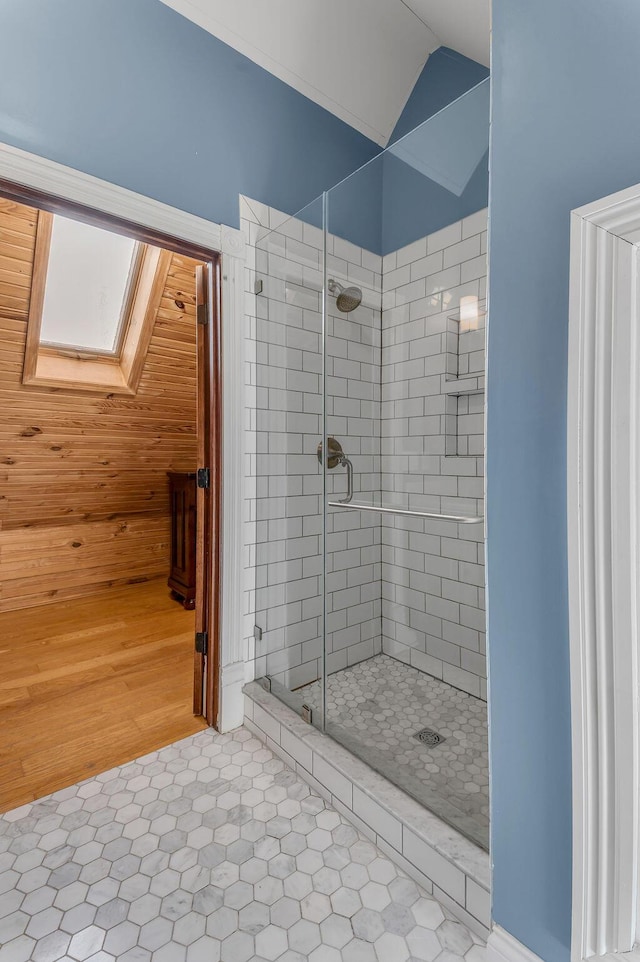 bathroom featuring tile patterned flooring, a shower with shower door, and vaulted ceiling with skylight