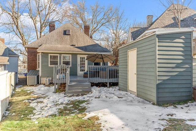 snow covered back of property featuring a storage shed and a deck