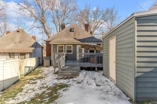 snow covered property featuring a wooden deck and a storage unit