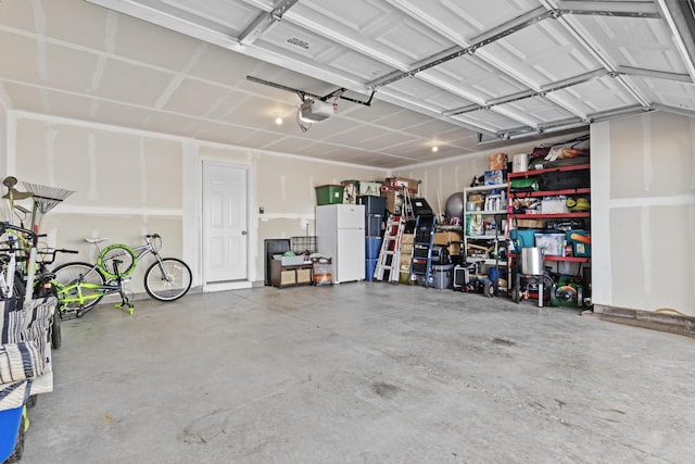 garage with a garage door opener and white refrigerator