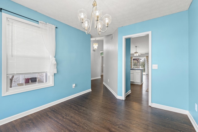 unfurnished dining area with ceiling fan with notable chandelier, dark wood-type flooring, and a textured ceiling