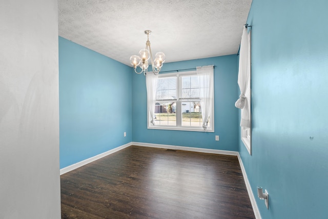 spare room with an inviting chandelier, hardwood / wood-style floors, and a textured ceiling