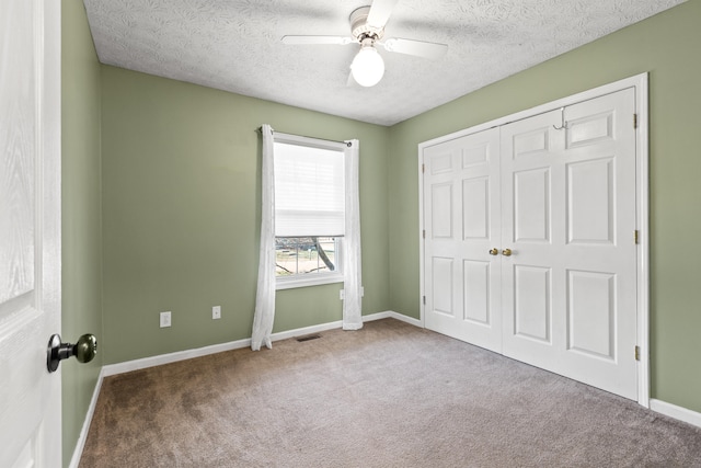 unfurnished bedroom featuring ceiling fan, a closet, light carpet, and a textured ceiling