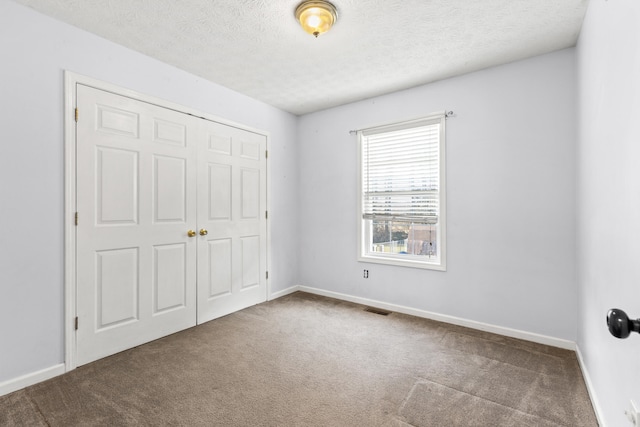 unfurnished bedroom featuring a closet, a textured ceiling, and carpet