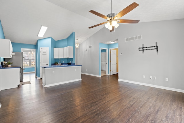 unfurnished living room featuring dark hardwood / wood-style flooring, vaulted ceiling, and ceiling fan