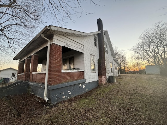 property exterior at dusk with a lawn and central air condition unit