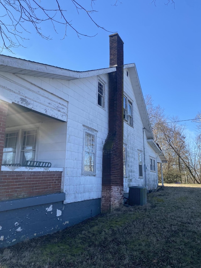 view of side of property with central AC and a lawn