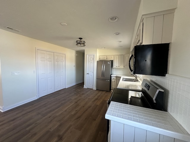 kitchen featuring dark hardwood / wood-style floors, tile countertops, white cabinetry, sink, and stainless steel appliances