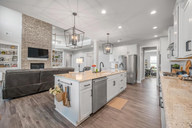 kitchen with white cabinetry, appliances with stainless steel finishes, a center island with sink, and pendant lighting