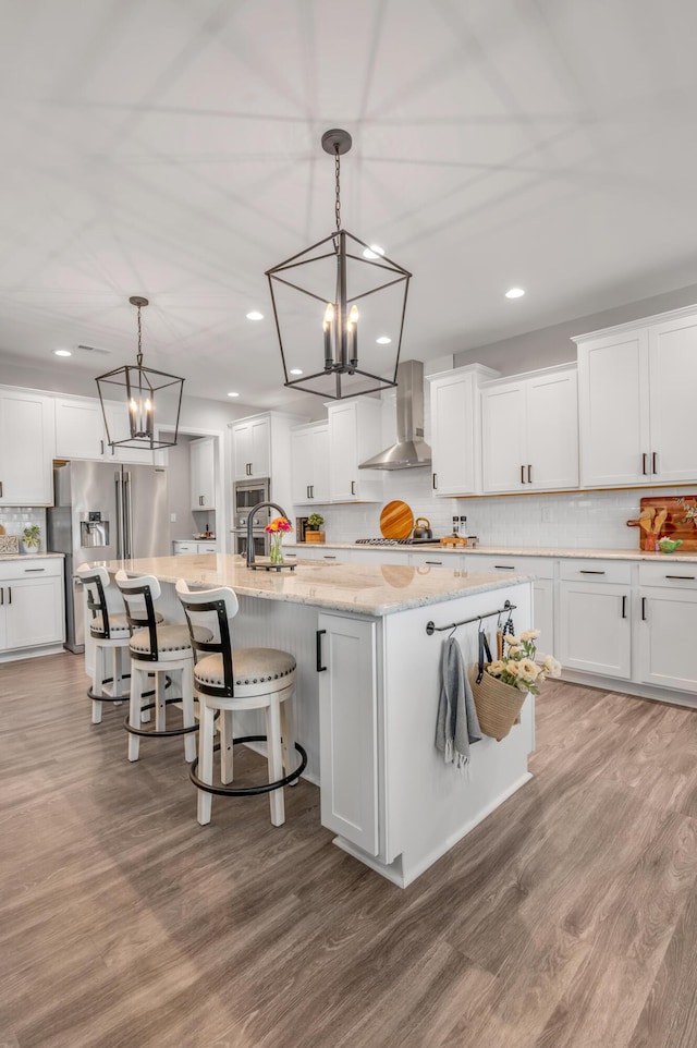 kitchen with white cabinetry, a large island, pendant lighting, and wall chimney exhaust hood