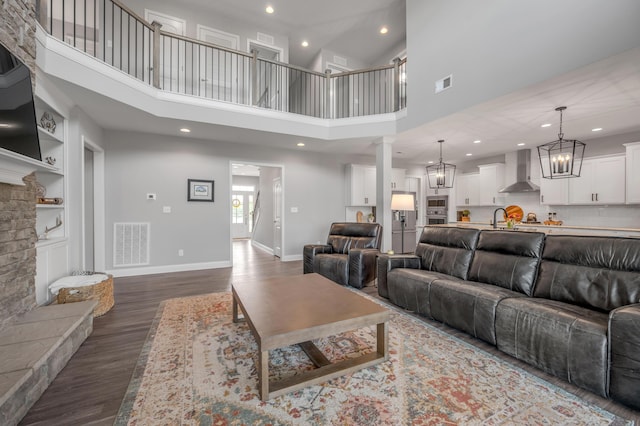 living room with a fireplace, decorative columns, wood-type flooring, sink, and a chandelier