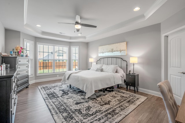 bedroom featuring dark hardwood / wood-style flooring, crown molding, a raised ceiling, and ceiling fan